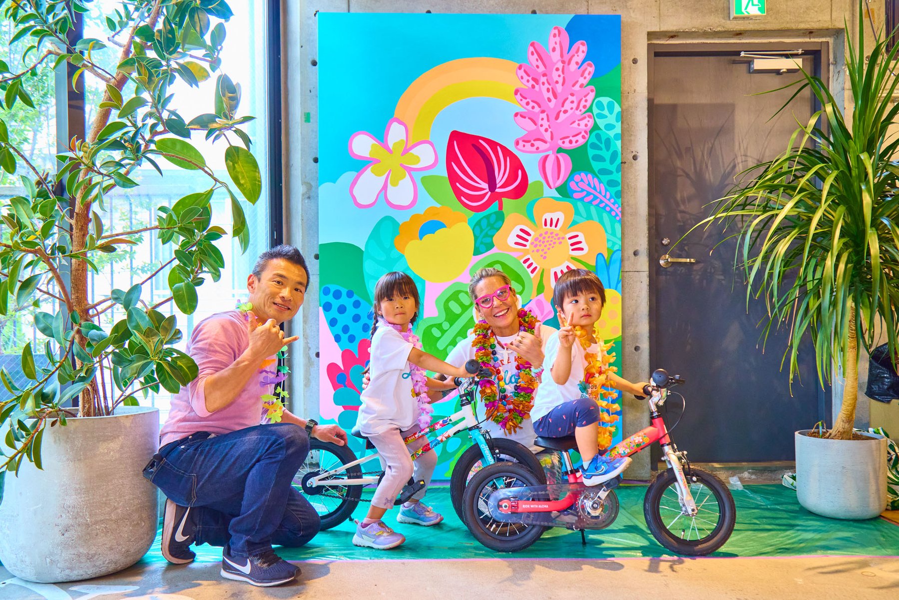 壁画の前でへんしんバイクにまたがる子どもたちと家族