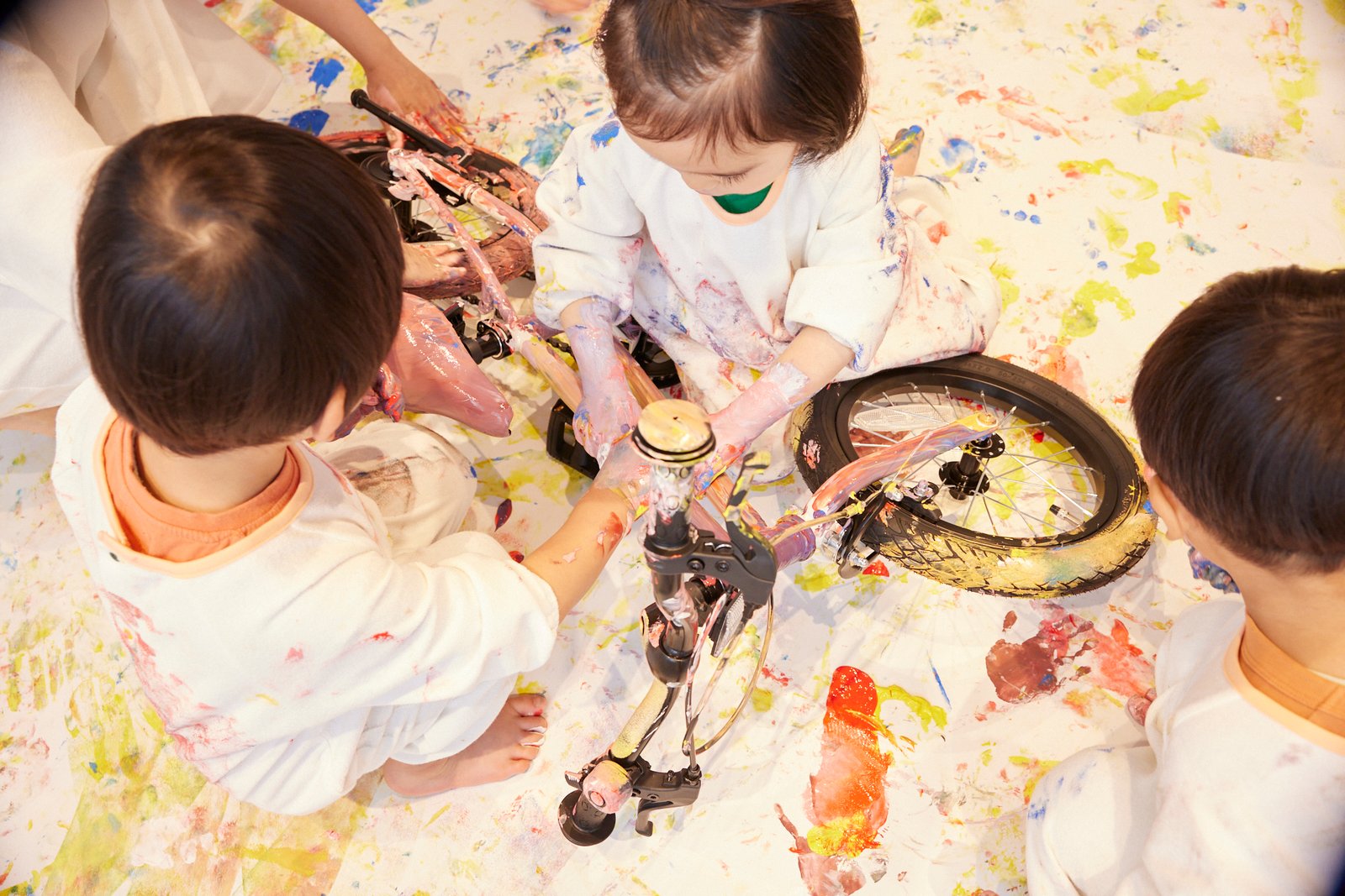 絵の具まみれのへんしんバイクを囲んでおえかきする子どもたち