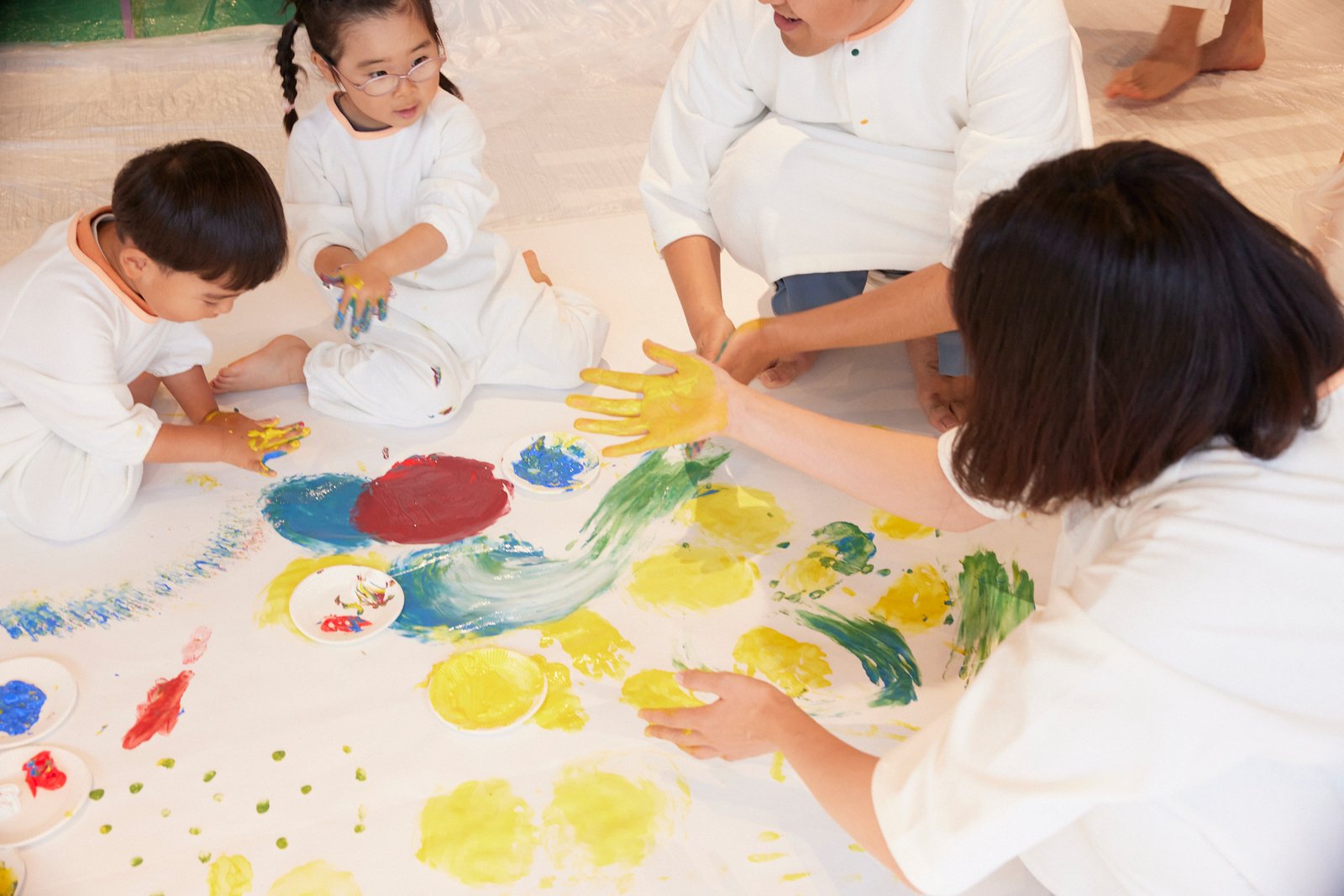床いっぱいの紙に親子で手のひらで描く様子