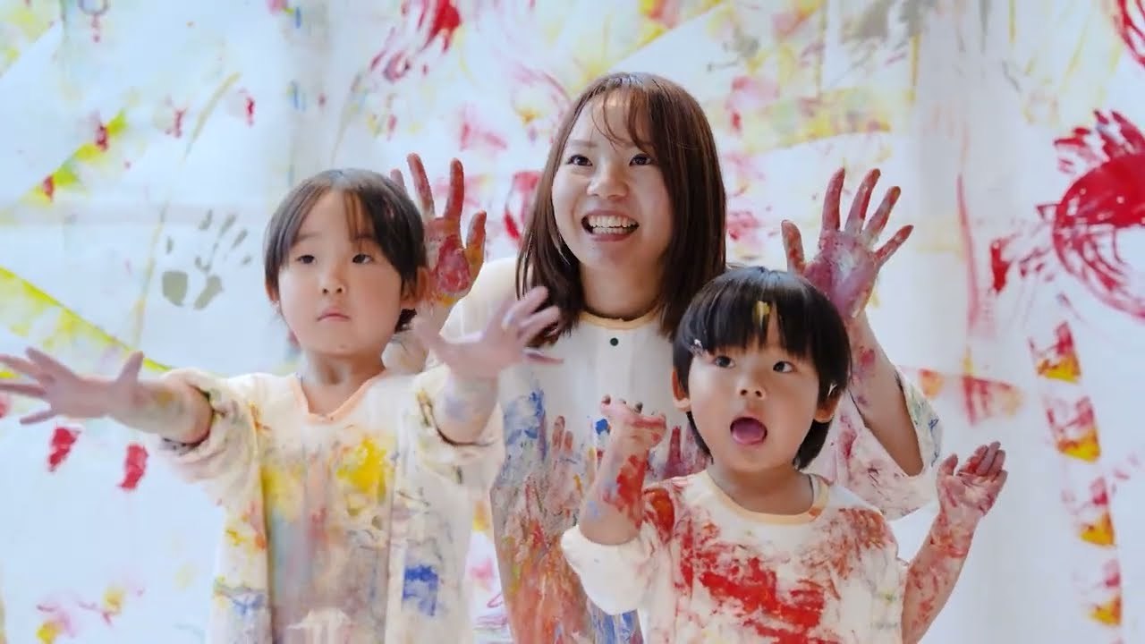 絵の具だらけになって手を挙げて笑う親子3人