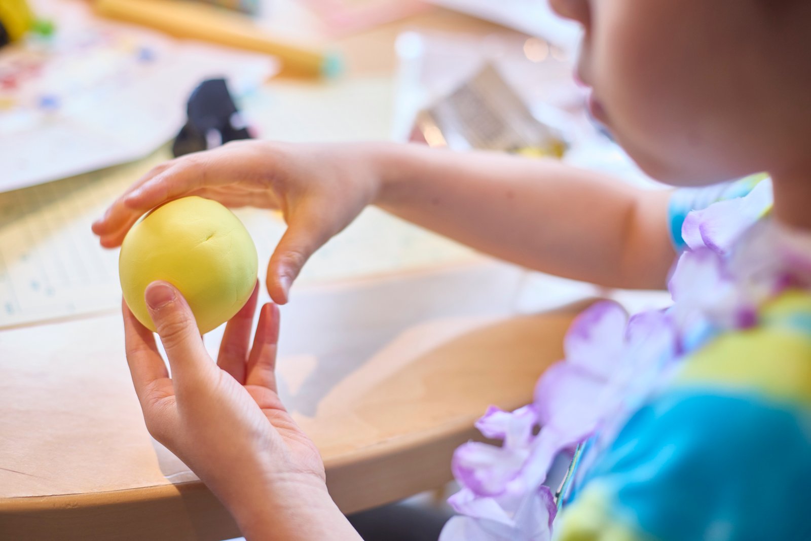 黄色いねんどを丸める子どもの手